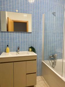 ein blau gefliestes Badezimmer mit Waschbecken und Badewanne in der Unterkunft Porto de Abrigo in Burgau