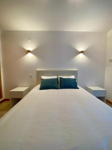 ein Schlafzimmer mit einem großen weißen Bett mit blauen Kissen in der Unterkunft Porto de Abrigo in Burgau + 10 Fotos
