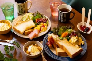 a wooden table with two plates of food and coffee at IMANO OSAKA SHINSAIBASHI HOSTEL in Osaka