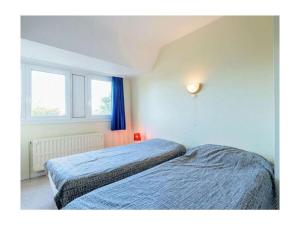 a bedroom with two beds and two windows at Holiday home in De Panne with barbecue in De Panne