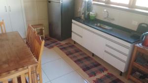 a kitchen with a sink and a table and a refrigerator at o sossego e aqui in Campos do Jordão