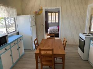a kitchen with a wooden table and a refrigerator at Beachcomber in Burrum Heads +4 photos