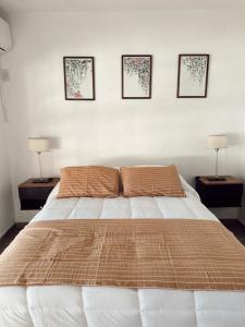 a bedroom with a bed with three pictures on the wall at El Ocaso in Esquina