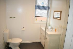 a white bathroom with a toilet and a sink at Comfy Apartment with carpark 2 minutes to CBD in Hobart