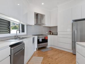 a white kitchen with a sink and a refrigerator at Oceanfront Beauty in Lilli Pilli in Surf Beach