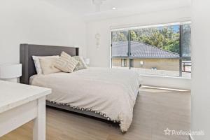 a bedroom with a bed and a large window at Bay Dream. in Malua Bay