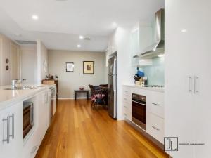 a kitchen with white cabinets and a wooden floor at The Sandcastle in Long Beach +17 photos