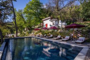 Una piscina con sillas y sombrillas al lado de una casa. en Villa Alceo, en Viggiù