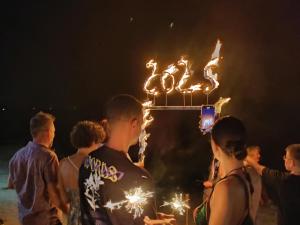 a group of people standing around a cake with sparklers at Baan AoKao KohMak in Ko Mak