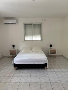 a white bedroom with a bed and two night tables at Villa Mare Café ROG in Le Gosier