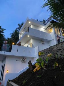 a large white house with two people on the balcony at SIRUS Resort Tagulandang in Kisihang