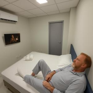 a man laying on a bed in a hospital room at Hotel Soberano in Taguatinga