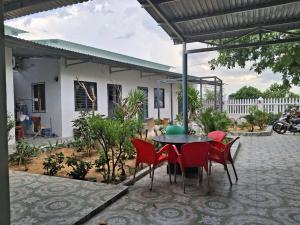 un patio avec une table et des chaises rouges dans l'établissement O'SEN Homestay, à Phước Hậu (1)