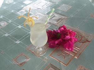 a drink in a glass on a table with flowers at Lonnoc ocean view beach bungalows in Hog Harbour