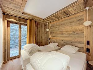 a bedroom with two beds and a wooden wall at Appartement neuf 7 pers, 3 chambres avec balcon et parking à Val-d'Isère - FR-1-519-43 in Val dʼIsère