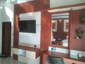 ein Wohnzimmer mit einem TV und einem Spiegel in der Unterkunft Coconut Hill Cottage in Nusa Penida