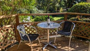 a table with a bottle of wine and two chairs on a deck at Amberlyn Escapes in Killcare