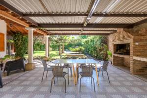 a patio with a table and chairs and a fireplace at Fliphaus Alzaga 5100 - 4 Bd House Pool BBQ Daily Housekeeping! in Mendoza