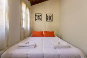 a bedroom with a large white bed with orange pillows at Fliphaus Alzaga 5100 - 4 Bd House Pool BBQ Daily Housekeeping! in Mendoza +17 photos