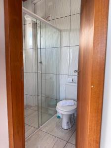 ein Badezimmer mit Toilette und Glasdusche in der Unterkunft Chácara Cidade da Divina Misericórdia in Araucária