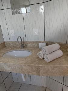 ein Badezimmer mit einem Waschbecken und Handtüchern auf der Theke in der Unterkunft Chácara Cidade da Divina Misericórdia in Araucária