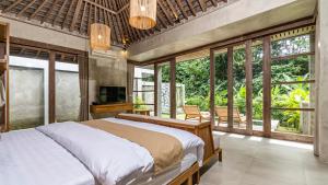 a bedroom with a large bed in a room with windows at Anggrek villa Ubud in Ubud