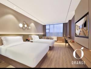 una camera d'albergo con due letti e una tv di Orange Hotel Beijing Yizhuang Rongjing West Street a Pechino