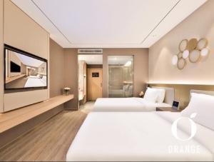 una camera d'albergo con due letti e una televisione di Orange Hotel Beijing Yizhuang Rongjing West Street a Pechino