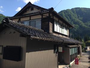 a house with a roof with mountains in the background at Guest House YAMASHITA-YA in Nanto