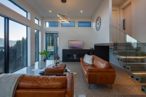 a living room with leather furniture and a glass table at Sky Villa A in Queenstown