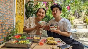 two men sitting at a table with a bowl of food at đất phú homestay phú yên in Ða Ngủ (2)