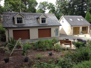 a house with two garage doors in a yard at The BurnHowf apartment in Balloch