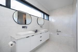 a white bathroom with a sink and a mirror at The Executive in Caulfield South in Melbourne +30 photos