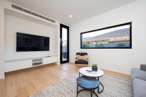 a living room with a couch and a tv at The Executive in Caulfield South in Melbourne