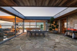 a patio with a table and chairs and a pool at Waiheke Island Coastal Retreat in Waiheke Island