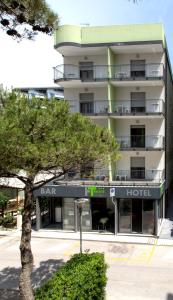 un hotel con un árbol delante de él en Hotel Trieste Mare, en Lignano Sabbiadoro