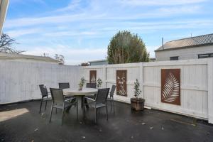 a patio with a table and chairs and a fence at Arbor Villa - Greytown Holiday Home in Greytown