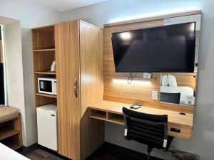 a room with a desk with a large flat screen tv at Microtel Inn & Suites by Wyndham Tuscaloosa East in Cottondale