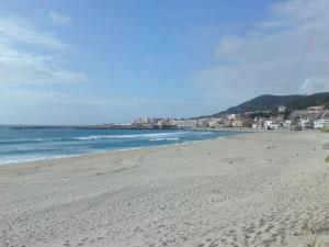 una playa con el océano y una ciudad en el fondo en Apartamentos Turísticos Vila Praia en Vila Praia de Âncora