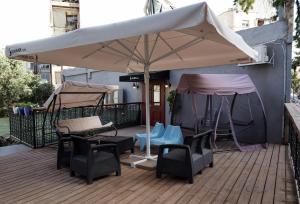 un grande ombrellone bianco su una terrazza con sedie e tavoli di Johnny Hotel a Gerusalemme