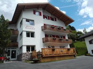 a large white building with a wooden balcony at Pension Sonnalp in Ortisei