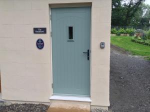 una porta blu sul lato di un edificio di The BurnHowf apartment a Balloch