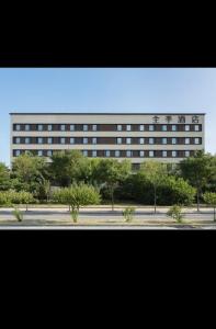 un edificio alto con árboles frente a una calle en JI Hotel Beijing Fangshan Changyang Aerospace City Electronics Technology Park, en Beijing