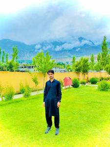 a man standing in the grass in a yard at The Metropolitan Hotel Gahkuch in Dargai +4 photos