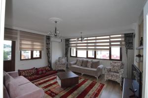 a living room with a couch and chairs and windows at Konaklar Apart Premium in Trabzon