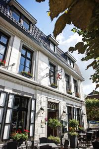 a white building with tables and chairs in front of it at In den Roden Leeuw van Limburg in Wittem