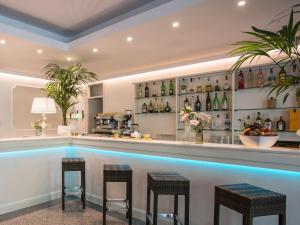 a bar with three stools in front of a pool at Hotel Wivien in Cesenatico