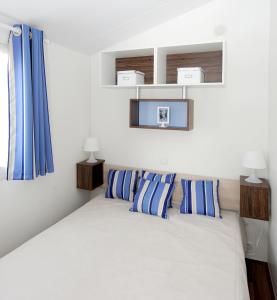 een slaapkamer met een bed met blauwe en witte kussens bij Camping Le Village de la Mer in Les Moutiers