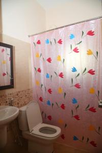 a bathroom with a toilet and a shower curtain with butterflies at Beachside Bliss - Villa 32 in Kilpettai +6 photos