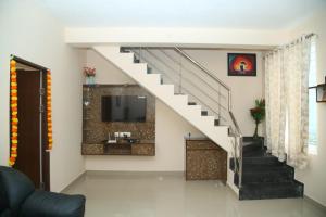 a living room with a staircase with a tv at Beachside Bliss - Villa 32 in Kilpettai